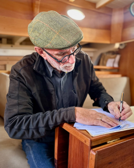 Graham Perkins inside a wooden vessel filling in survey documents.